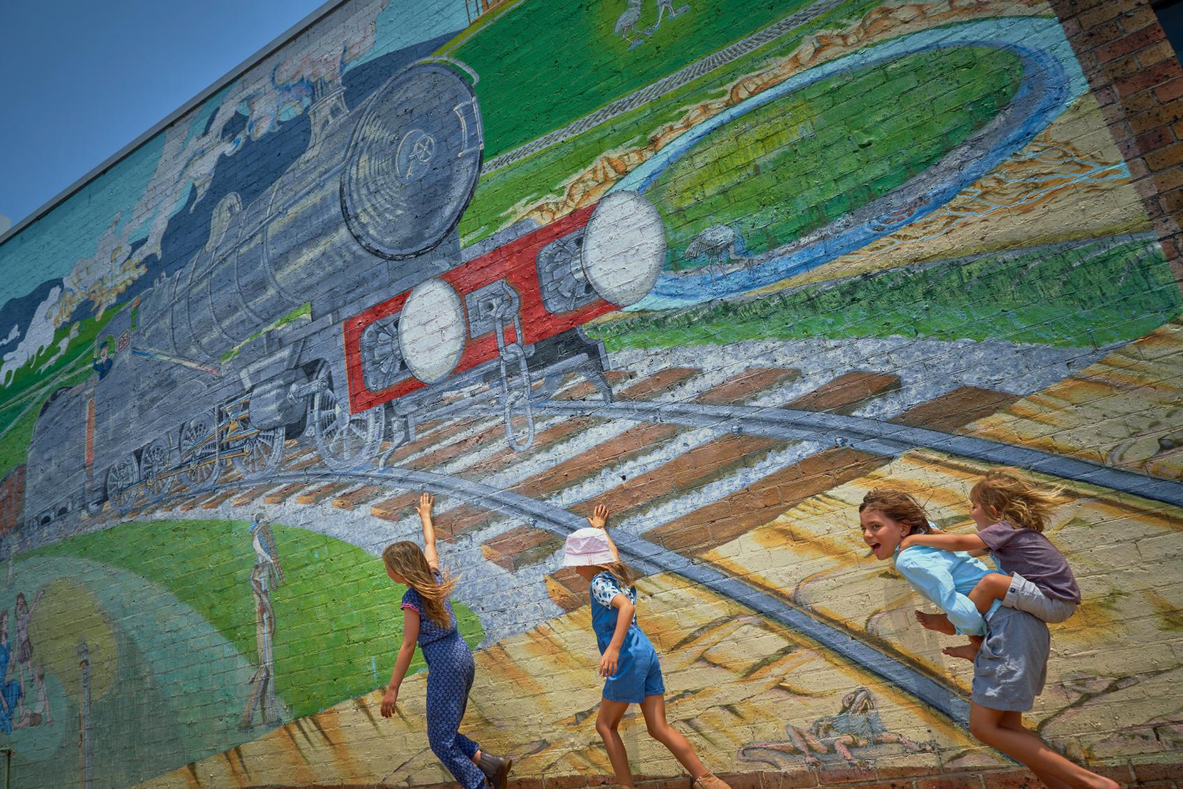 Artistically decorated laneway in Cessnock, NSW, with children walking by the wall