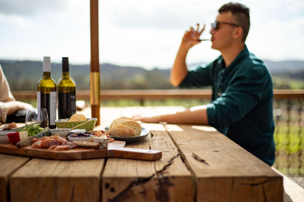 A man enjoys a glass of wine on the terrace of a vineyard in Pyrenees, Victoria