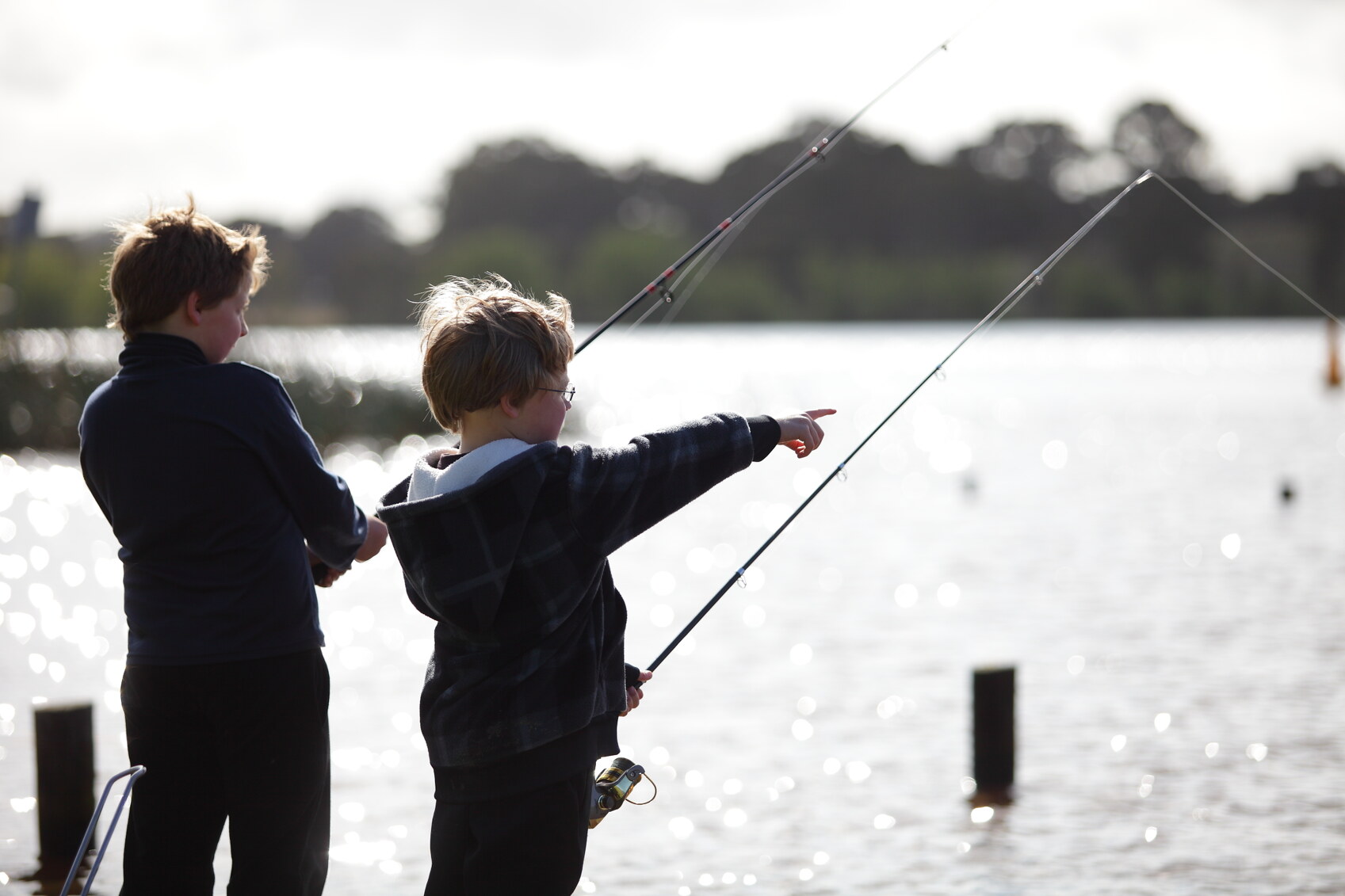 Two boys fishing as the sun sparkles on waves in Pyrenees Victoria