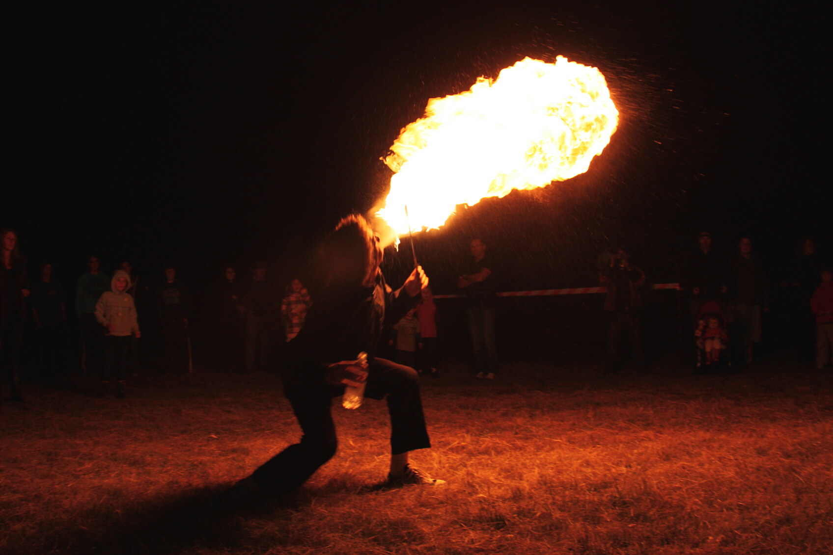 A crowd watch a fire eater perform at night at Party in the Pyrenees, Victoria